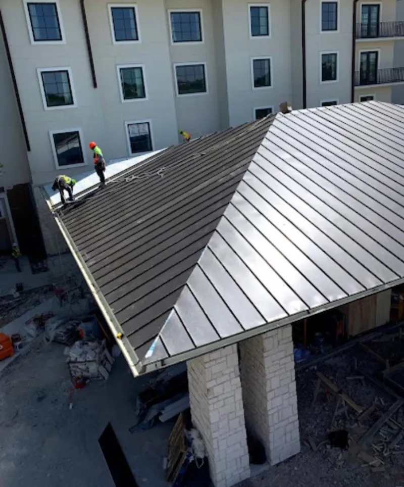 Crew installing standing seam metal roof panels on a commercial project in Jefferson